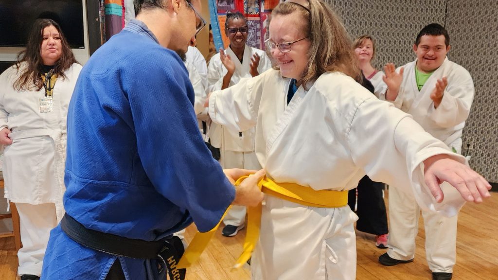 Member wearing a karate outfit is fitted with a yellow belt